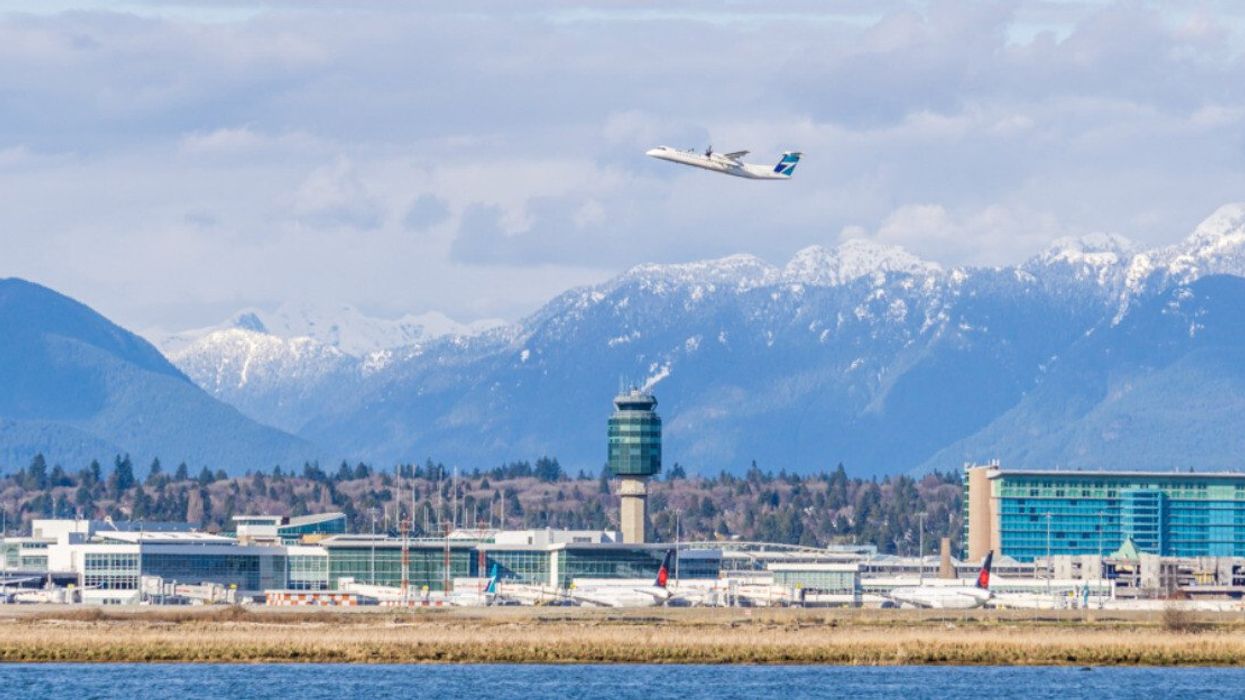 A plane taking off from an airport with mountains in the background.