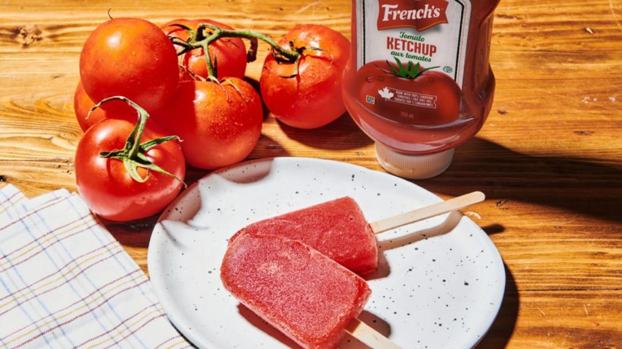 A plate holding two Frenchsicles, with tomatoes and ketchup behind it.
