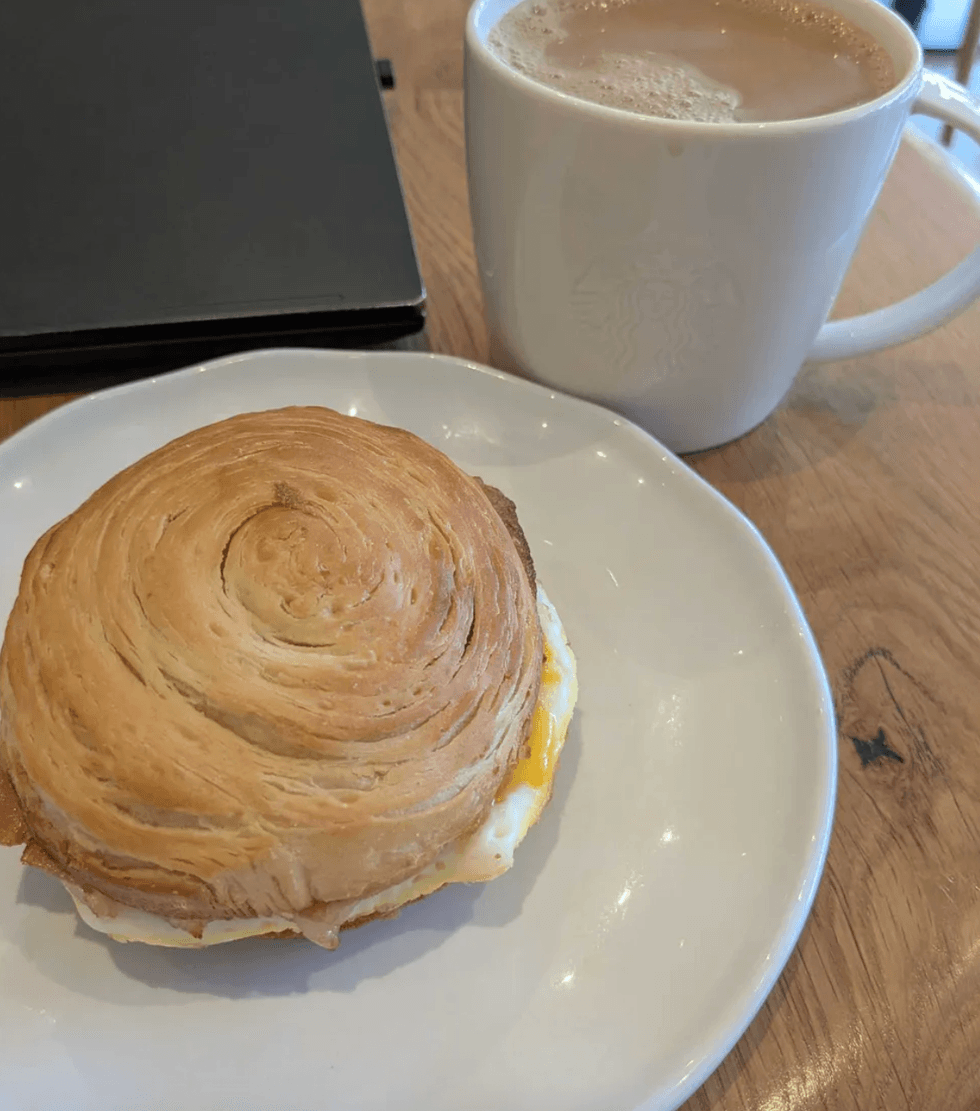 A plate with a sandwich on it and a mug of coffee.