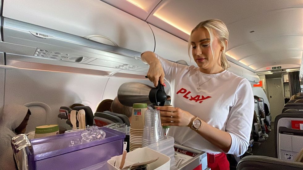 A Play Airlines flight crew member serving beverages during the flight.