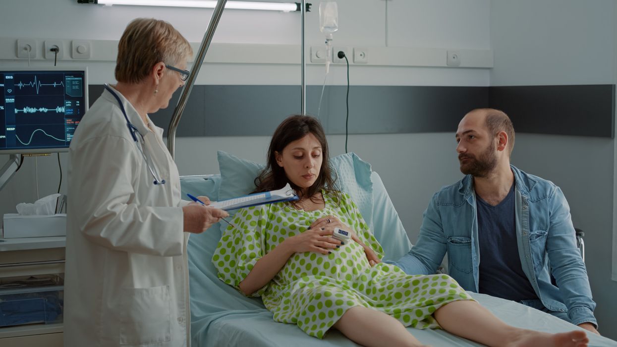A pregnant woman at the hospital with a man and a doctor.