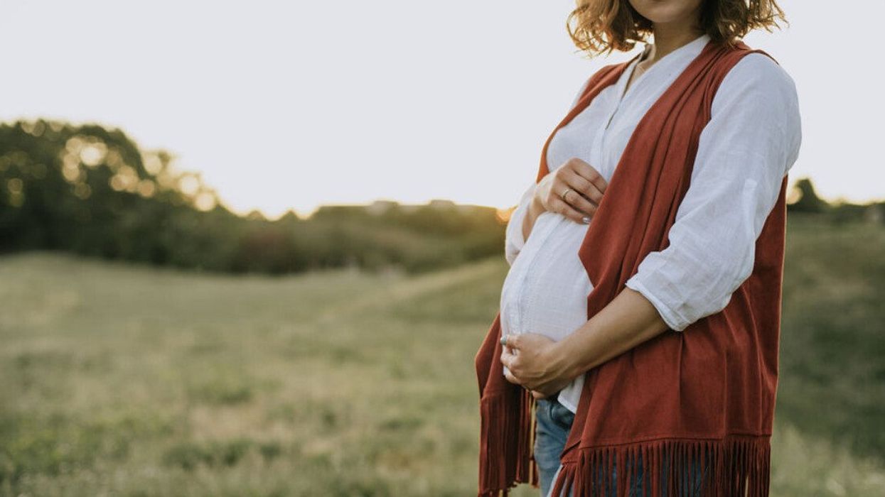 A pregnant woman in a cowboy outfit.