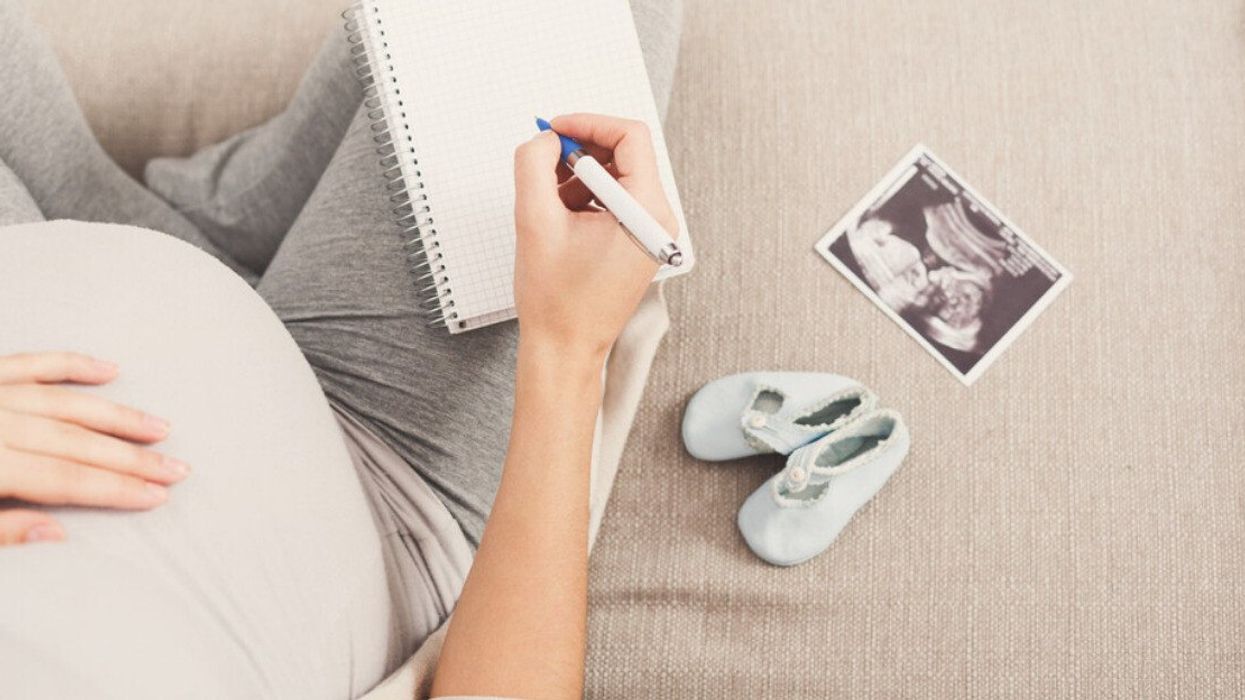 A pregnant woman writing baby names down.