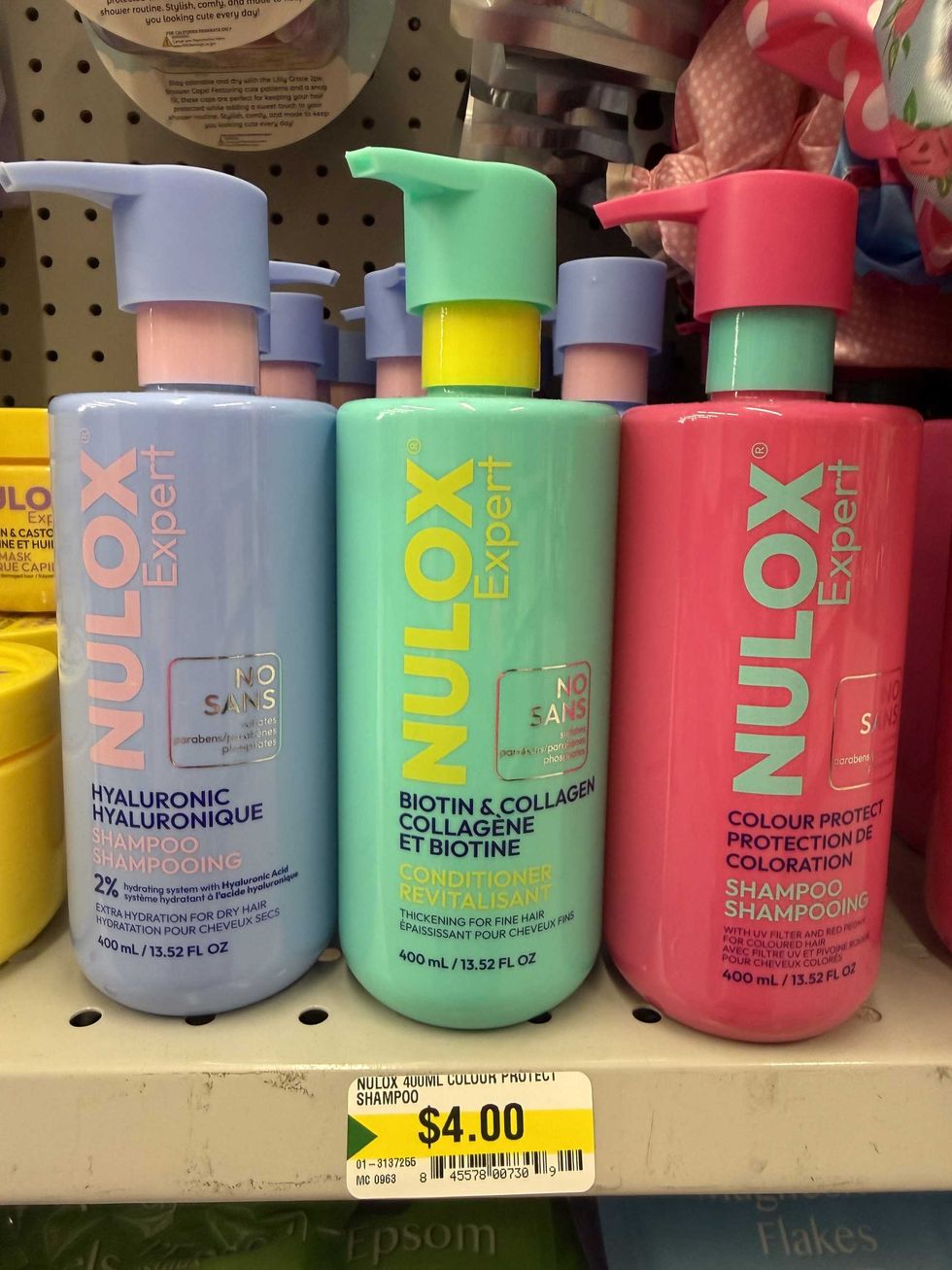 A purple, green and pink bottle with labels that say Nulox Expert shampoo and conditioner on a store shelf.