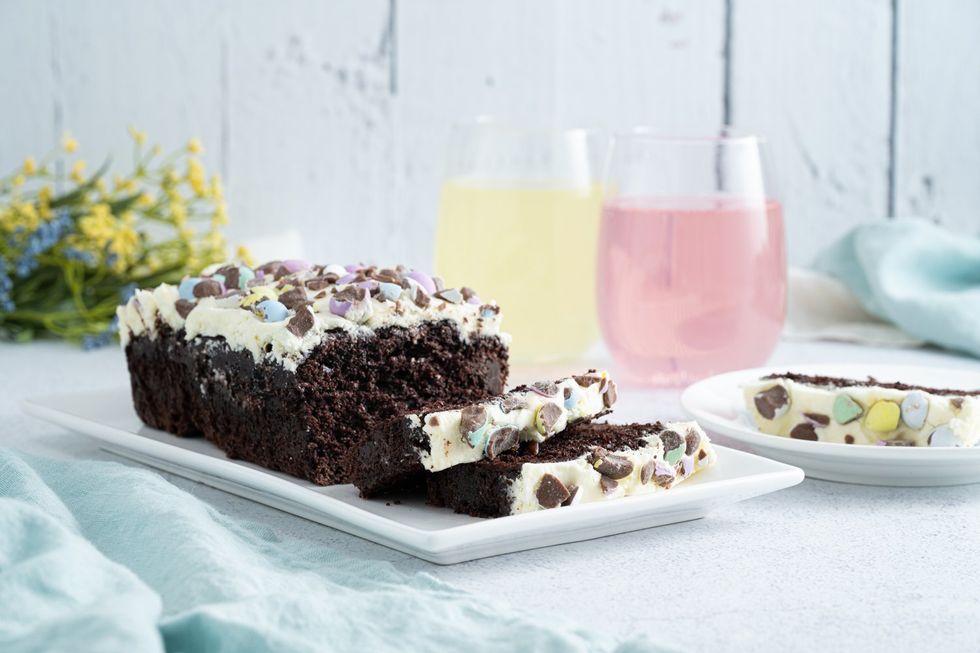 A rectangular chocolate cake decorated with colourful mini eggs and white icing.