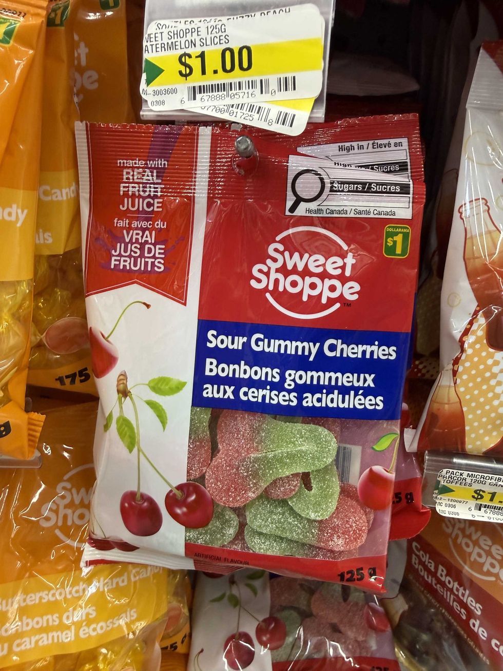 A red and white bag with a picture of cherries on it and a label reading sour gummy cherries.
