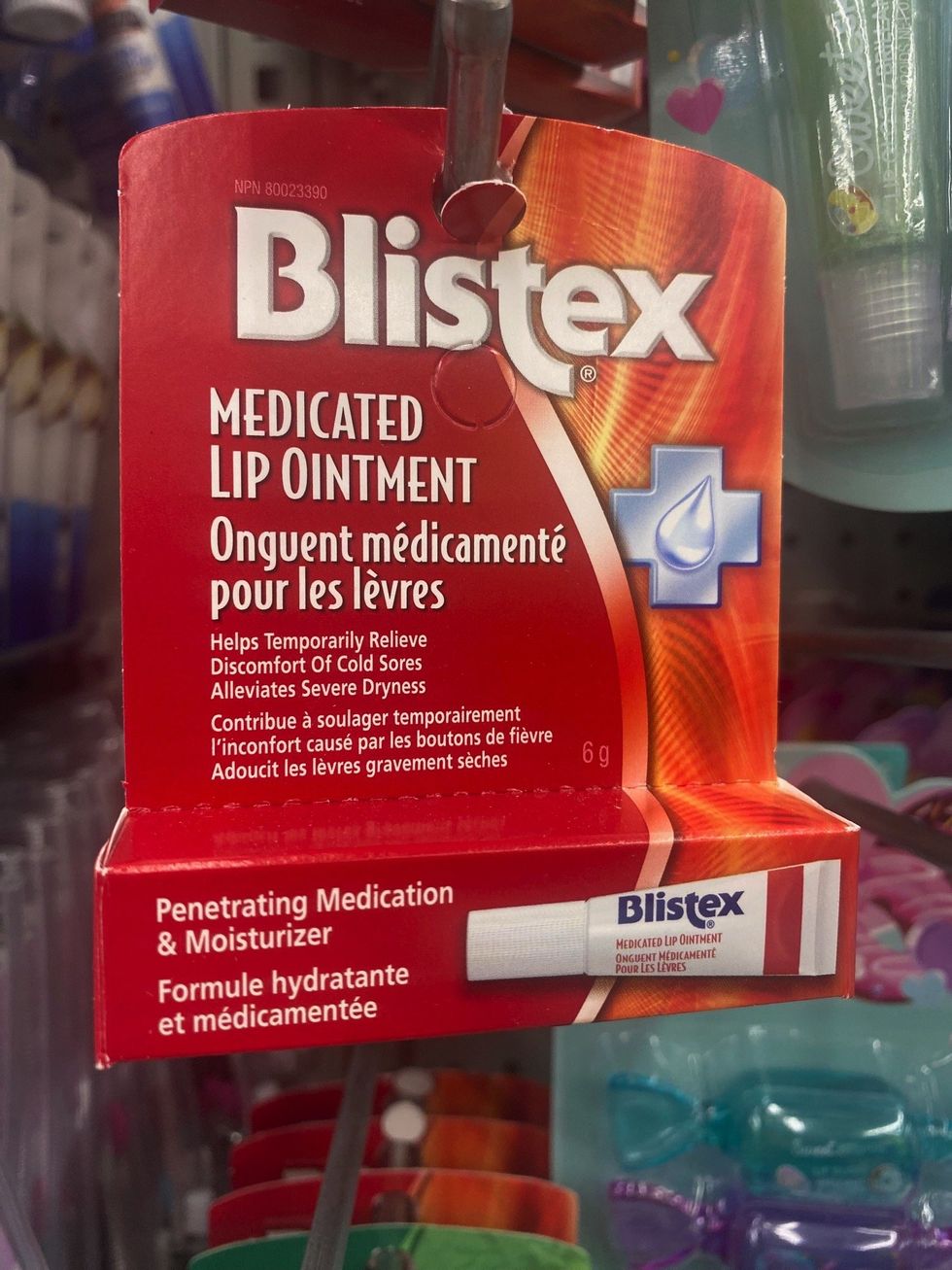 A red box with a tube or medicated lip ointment hanging on a store shelf.