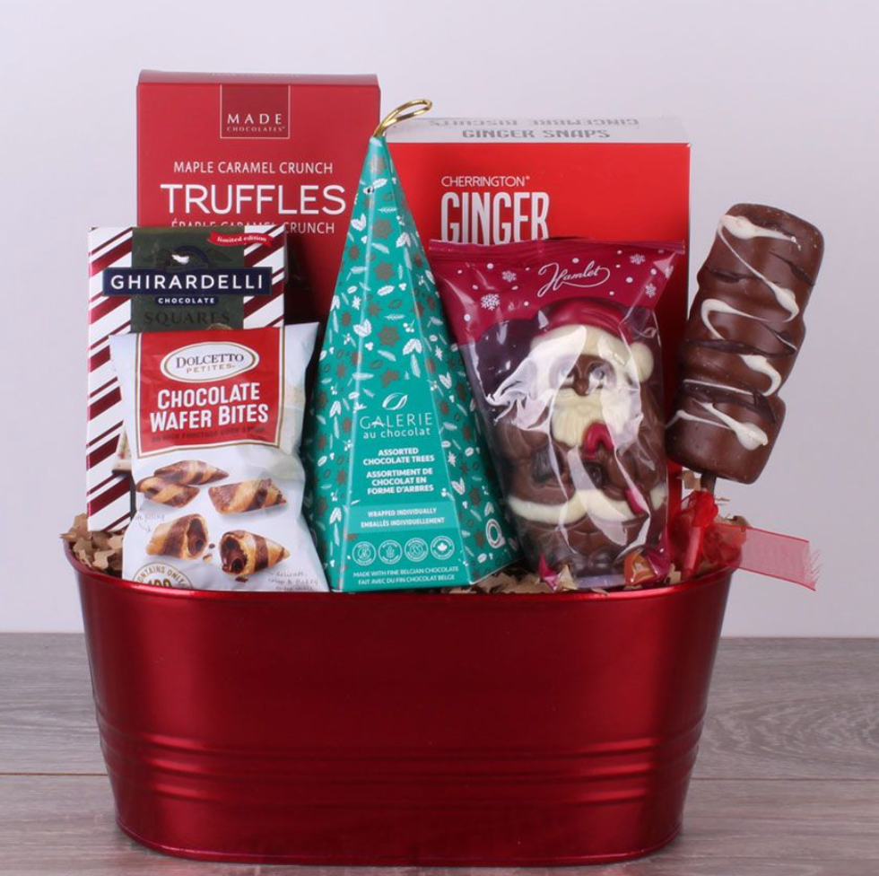 A red gift basket filled with items like a chocolate santa, a chocolate tree, chocolate wafer bites and truffles.