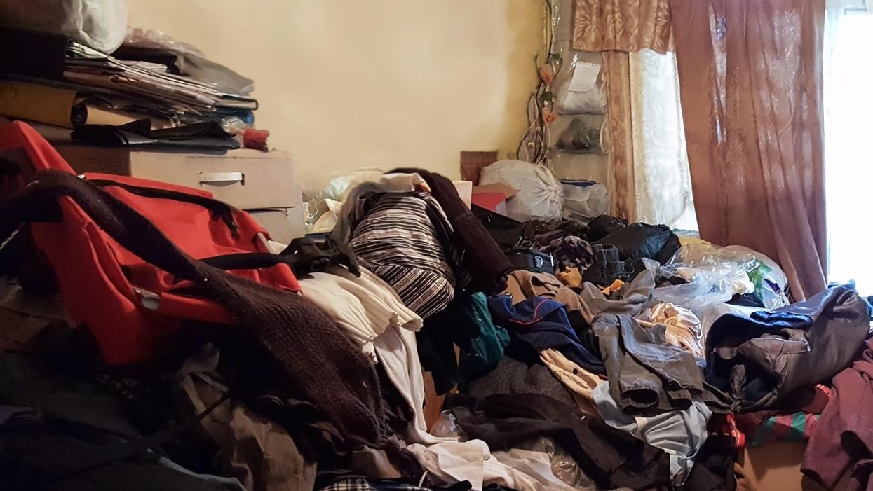 A room stacked with clothes and trash.
