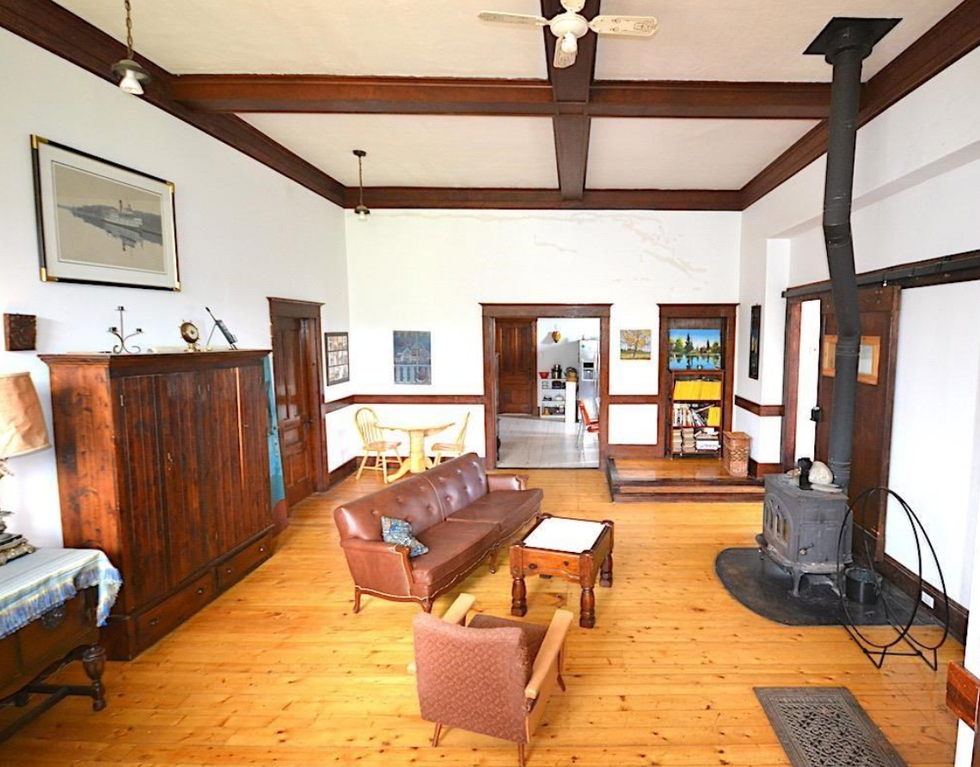 A room with a wood stove, multiple seats and hardwood floors.