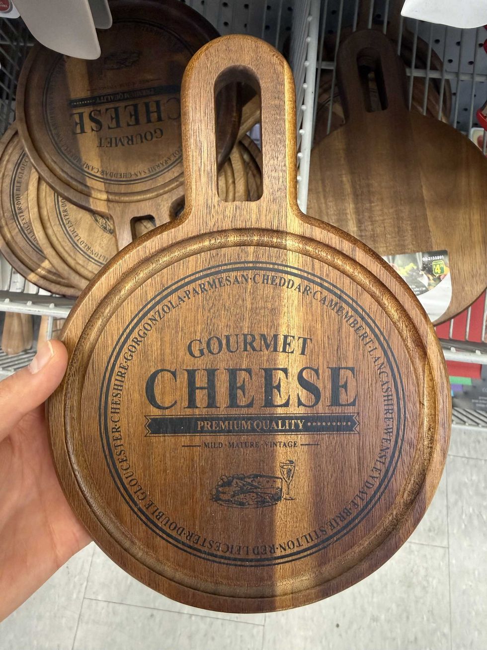 A round wooden board that says gourmet cheese on the front.