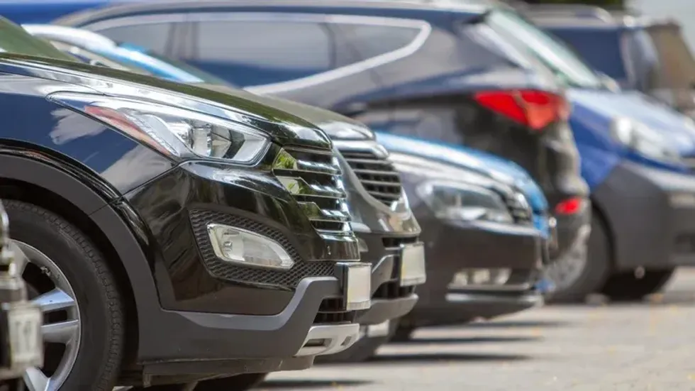A row of cars parked near curb on the side of the street on a parking lot.
