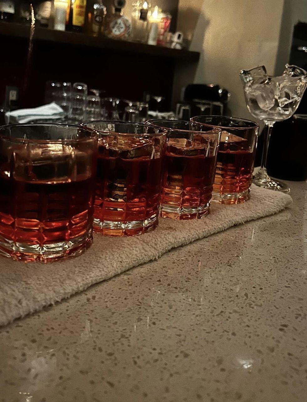A row of four Negronis set on a bar.