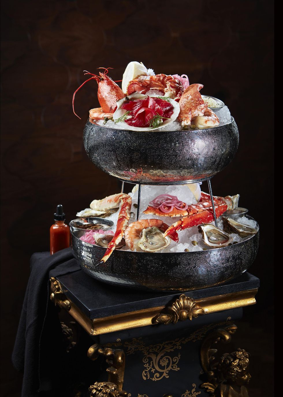 A seafood tower on a black and gold table.