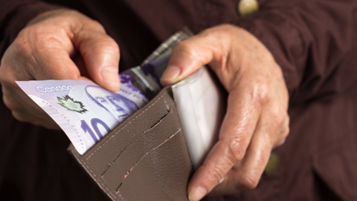A senior puts Canadian cash into a wallet.