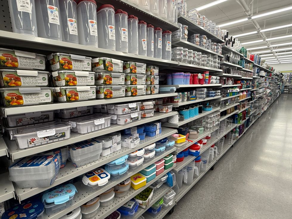 A shopping aisle in a store with shelves filled with tupperware containers.