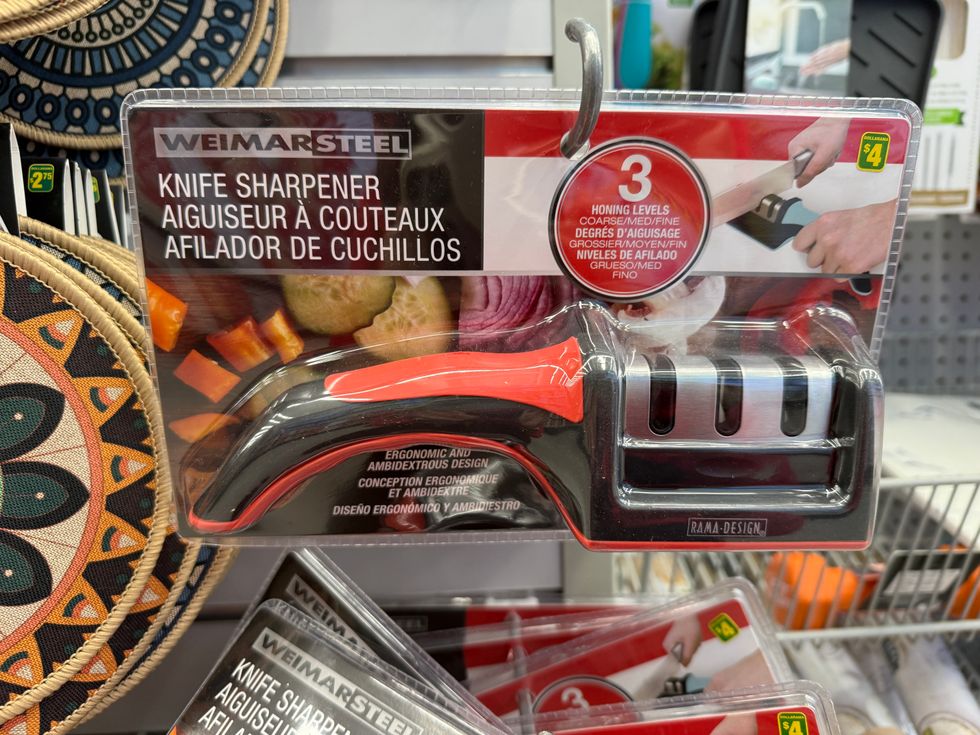A silver and black tool with a red and black handle in a package that says knife sharpener.