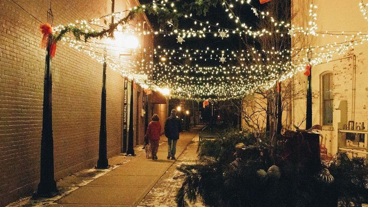 A small town street with a canopy of Christmas lights.