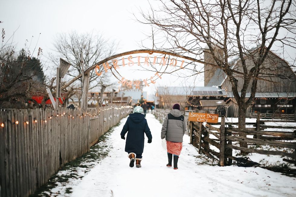 A snow covered lane leading to wooden chalets and a twinkly market.