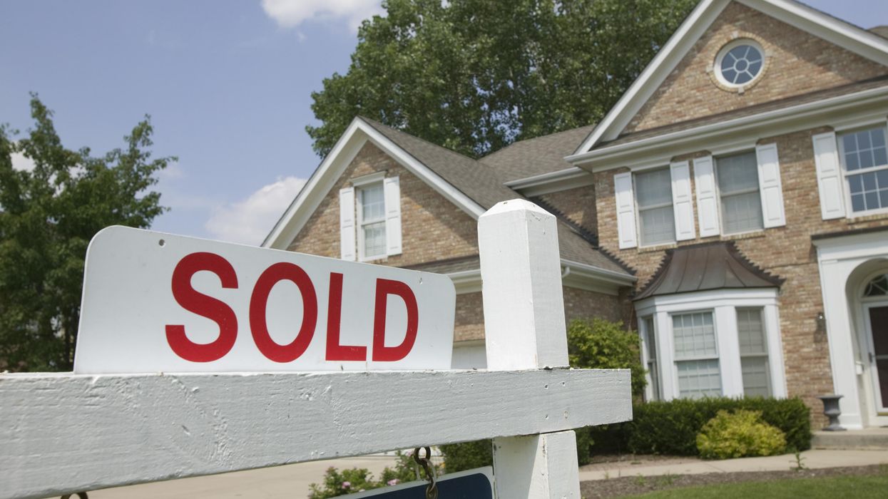 A "sold" sign in front of a house.