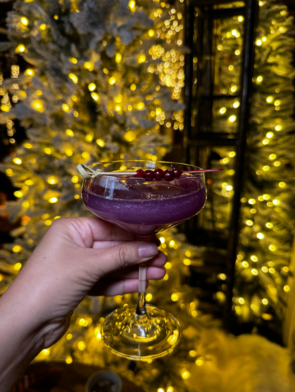 A sparkly purple cocktail at the Park Hyatt in Toronto with a Christmas tree in the background.