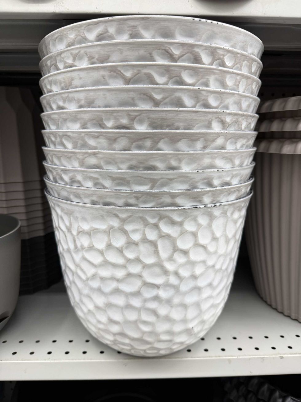 A stack of white and grey flower planters on a store shelf.