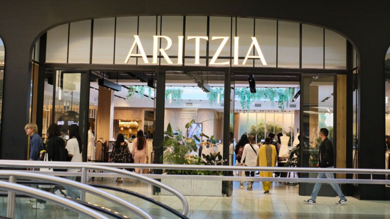A store at a mall with a sign that says Aritzia and people walking both into the store and outside the store.