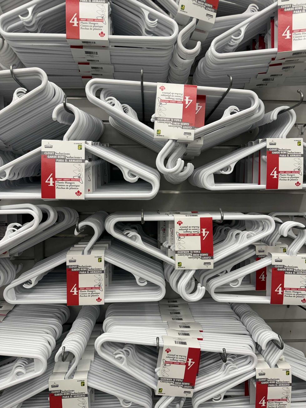 A store wall filled with hundreds of plastic white clothing hangers.