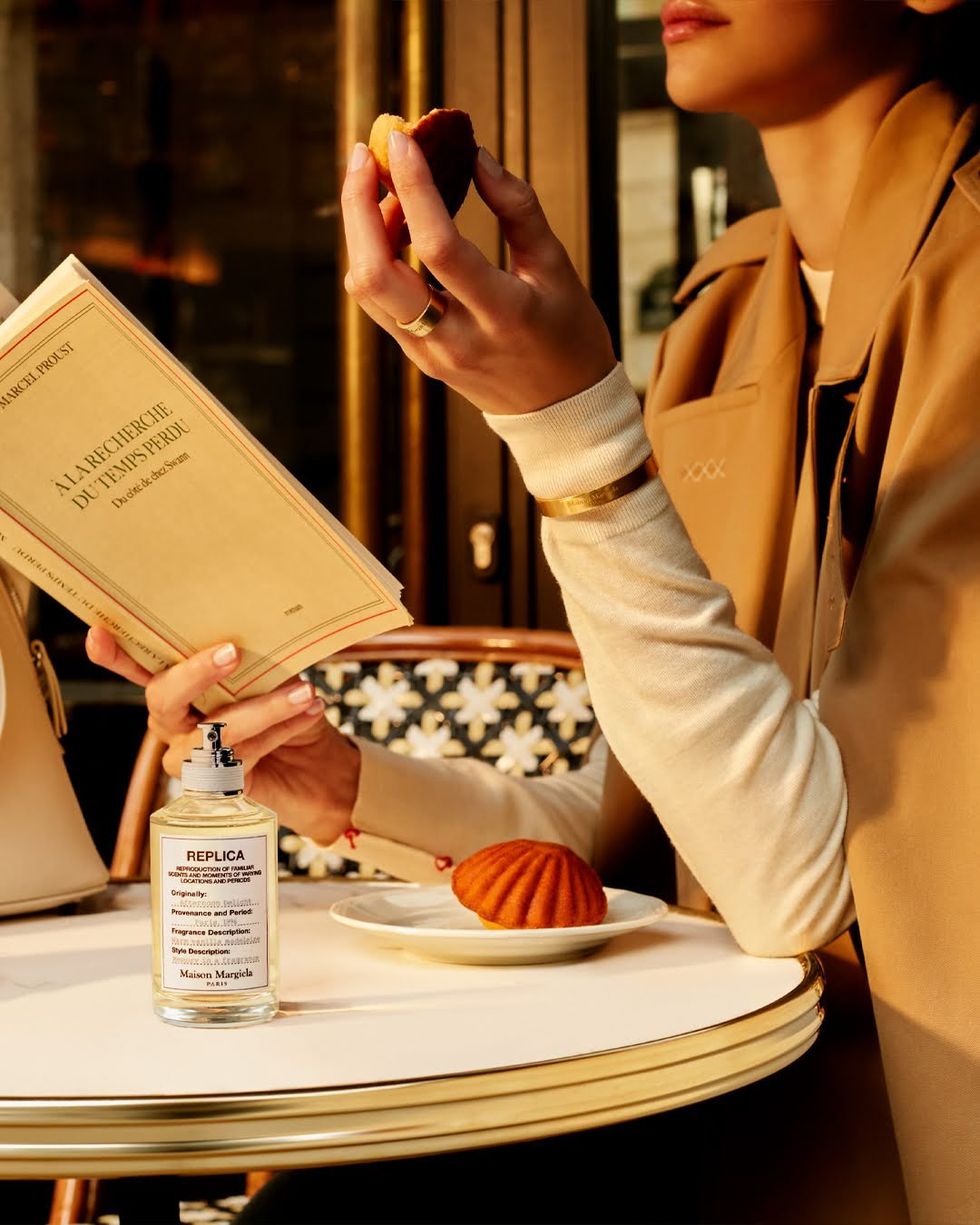 A stylish woman enjoys a madeleine at a Parisian cafe.