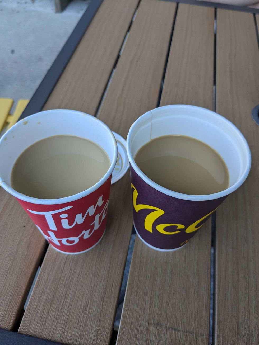 A Tim Hortons and McDonald's coffee cup side by side on a table