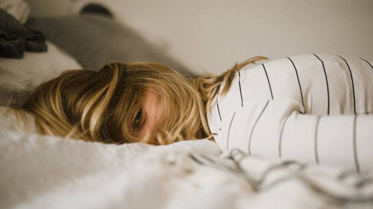 A tired person laying on a bed.