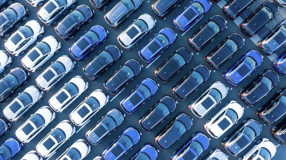 A top-down view of dozens of cars parked end to end in a densely packed parking lot.