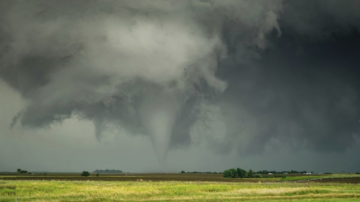 A tornado going over green fields.