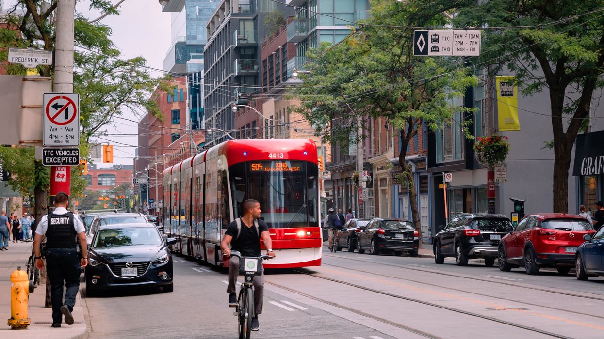 A Toronto road with someone on an e-bike next to a streetcar.