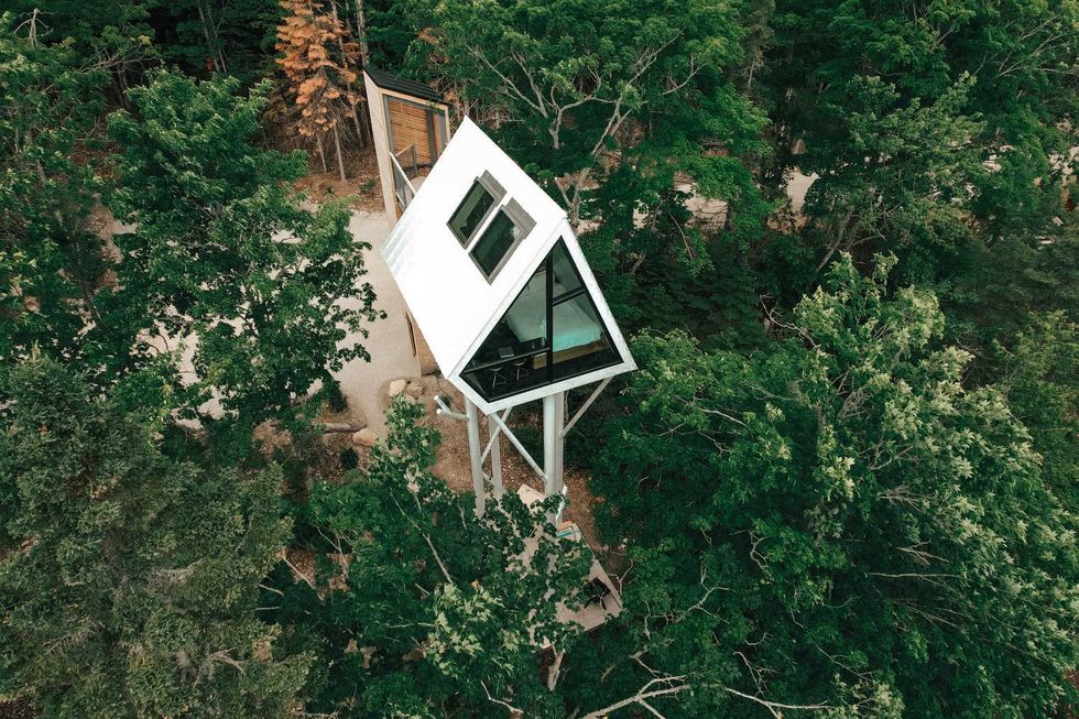 A treehouse with a steep roof surrounded by trees.