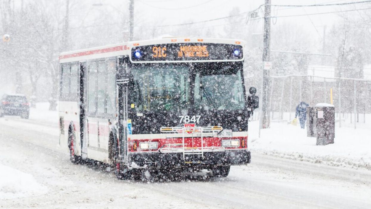 A TTC bus driving through a snow-covered street.