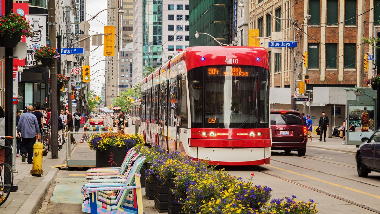A TTC streetcar drives along King street in Toronto, surrounded by spring flowers.