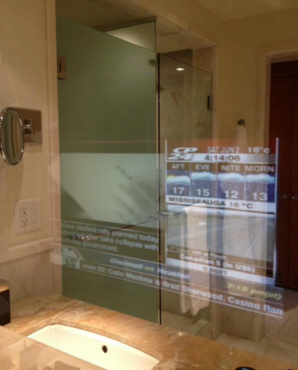 A TV embedded behind a bathroom mirror.