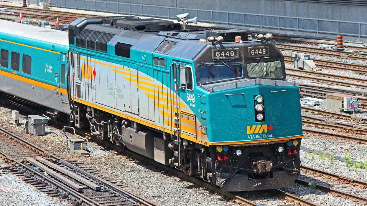 A VIA Rail Canada train moving along some tracks.