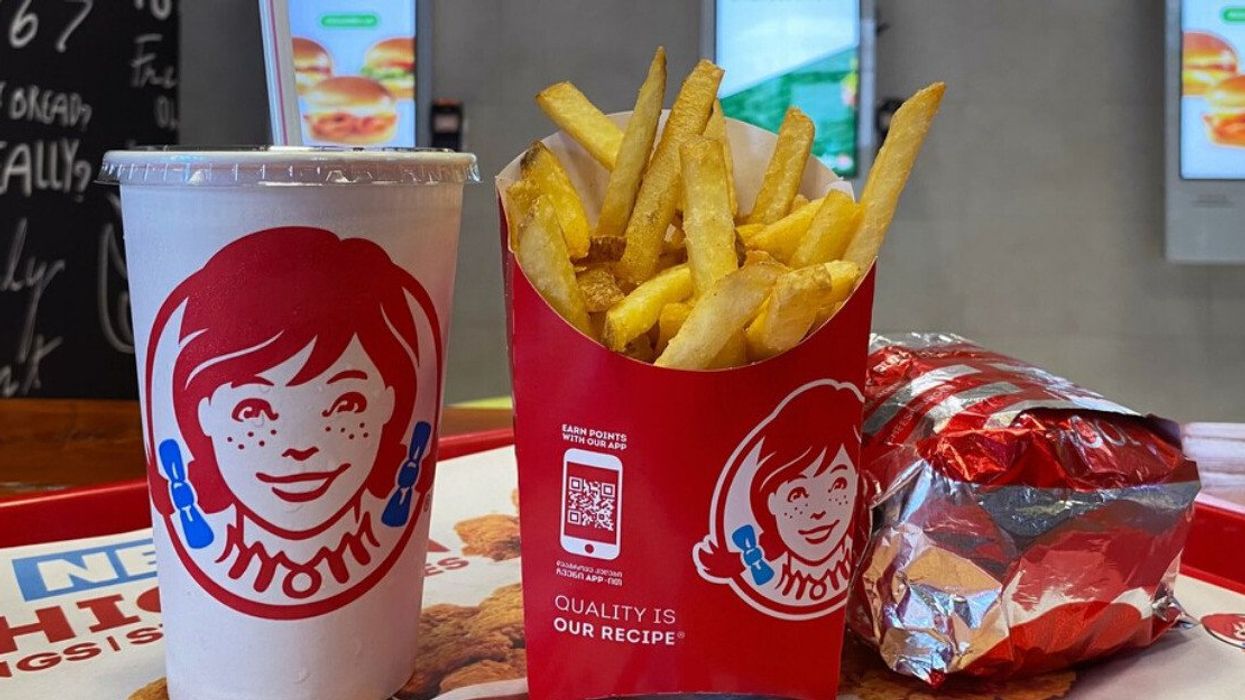 A Wendy's meal of fries, a wrapped burger and a drink on a tray.
