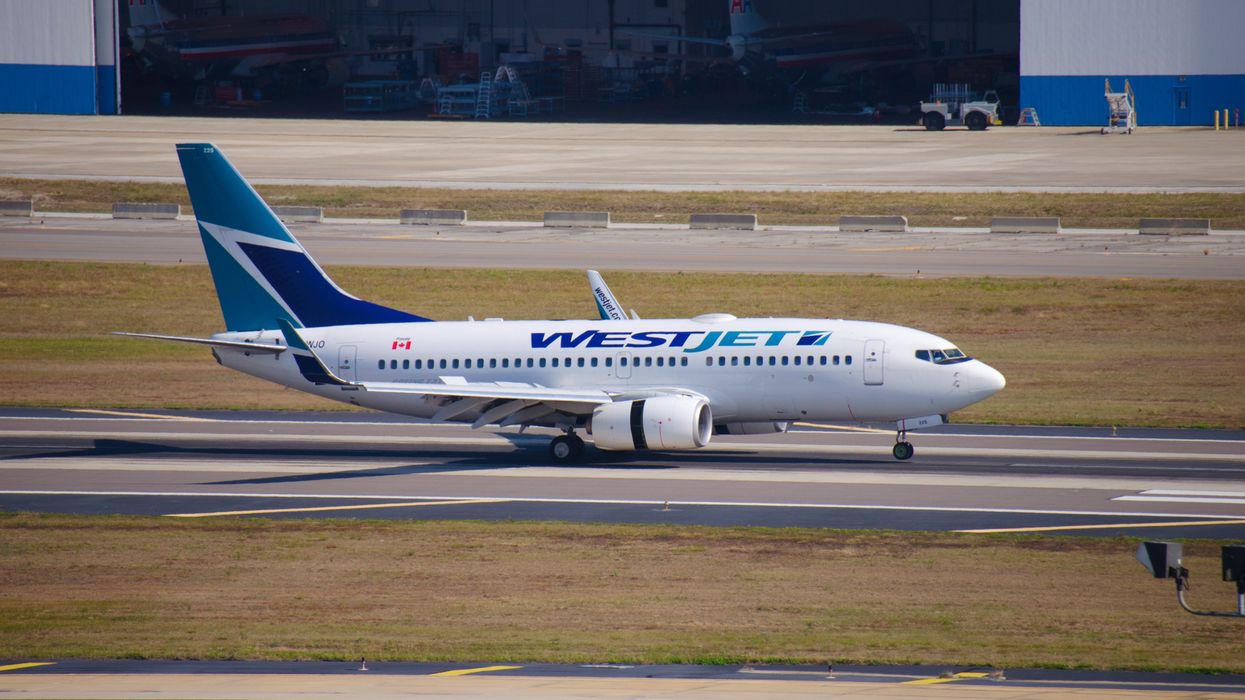 A WestJet plane landing at an airport.