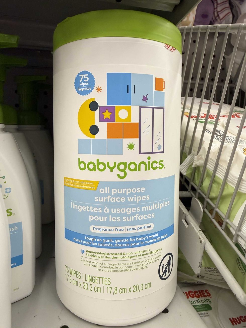 A white and blue tub on a store shelf that says \u200bBabyganics all purpose surface wipes at Dollarama.