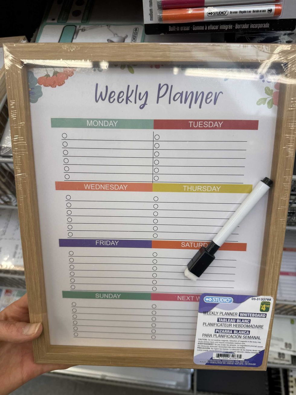 A white board with wooden frame and colourful sections with days on the week on it.