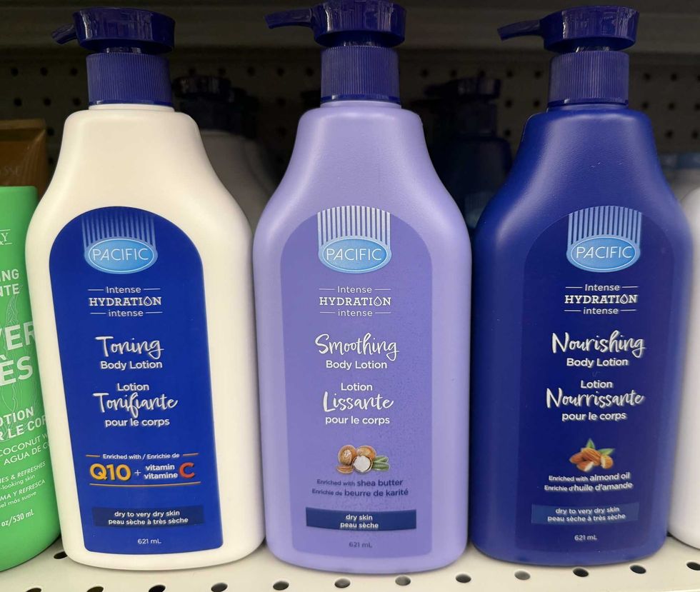 A white bottle with blue label, purple bottle and blue bottle of body lotion on a store shelf