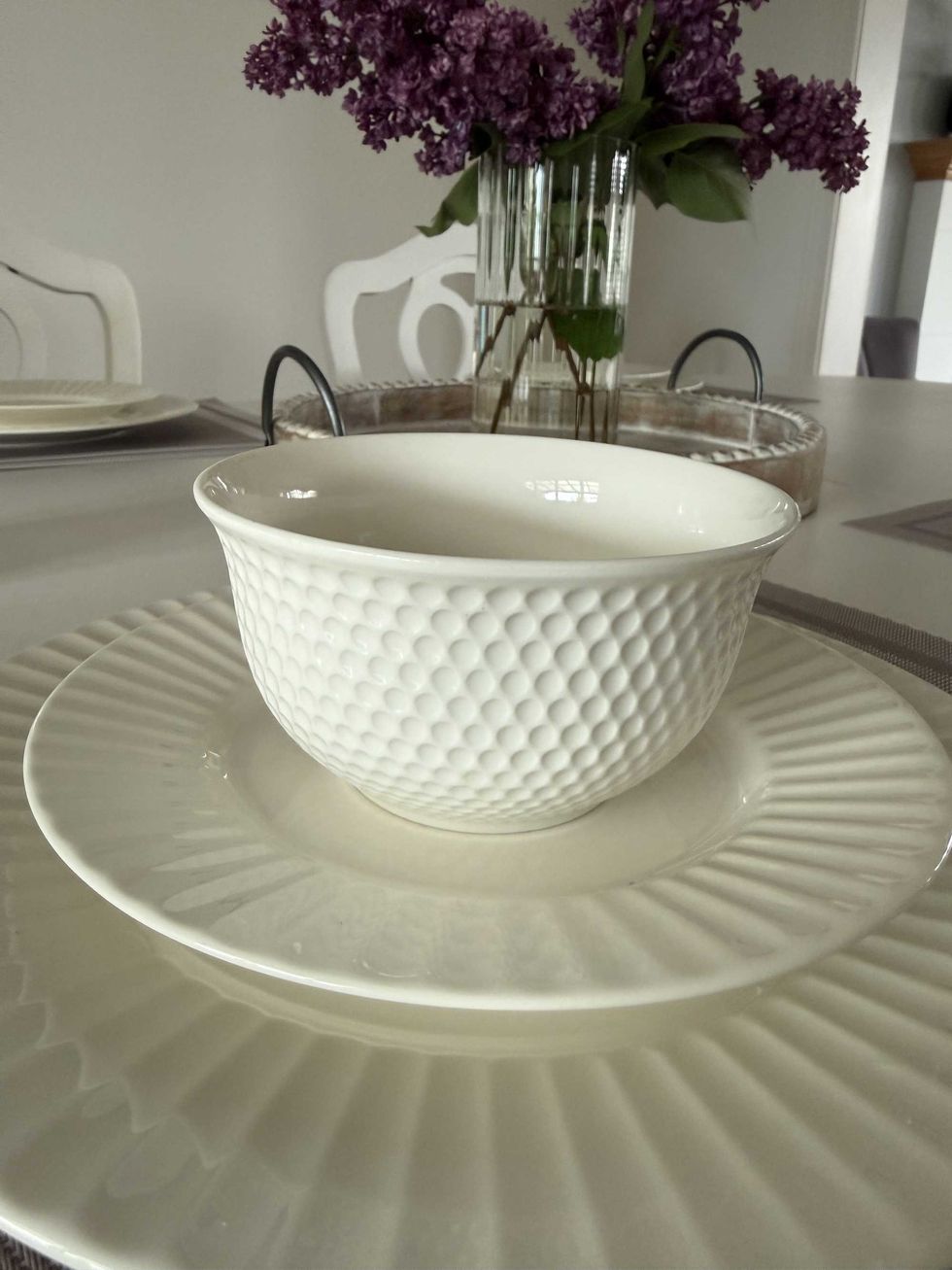 A white bowl stacked on top of two places on a dining table.