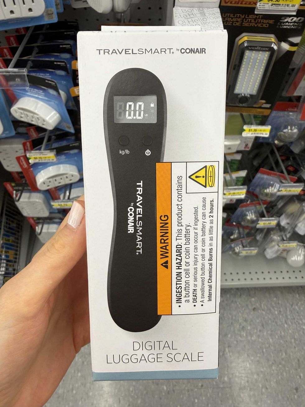 A white box with a photo of a black digital luggage scale on it.