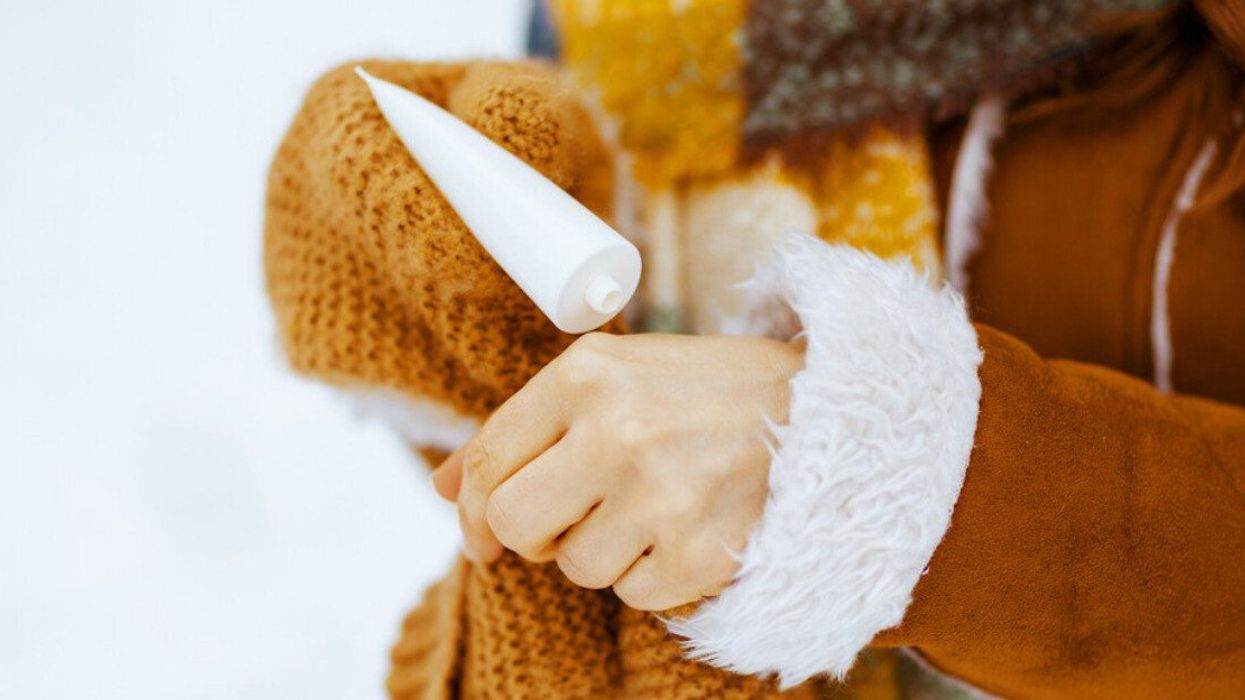 A woman applying hand cream while she's outside in the winter.