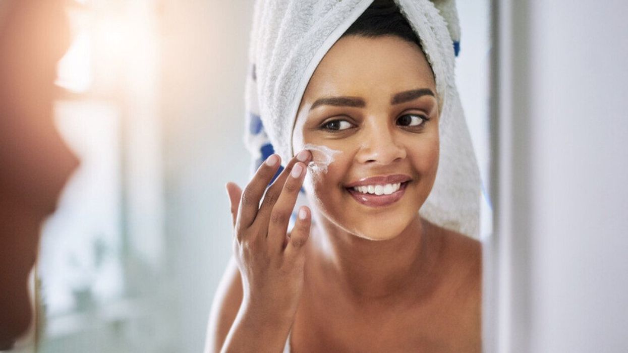 A woman applying moisturizer to her face.