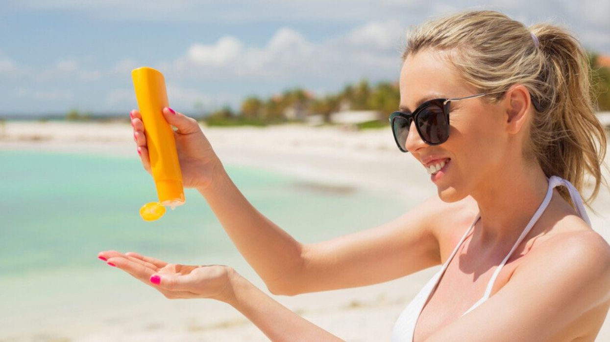 A woman applying sunscreen at the beach.