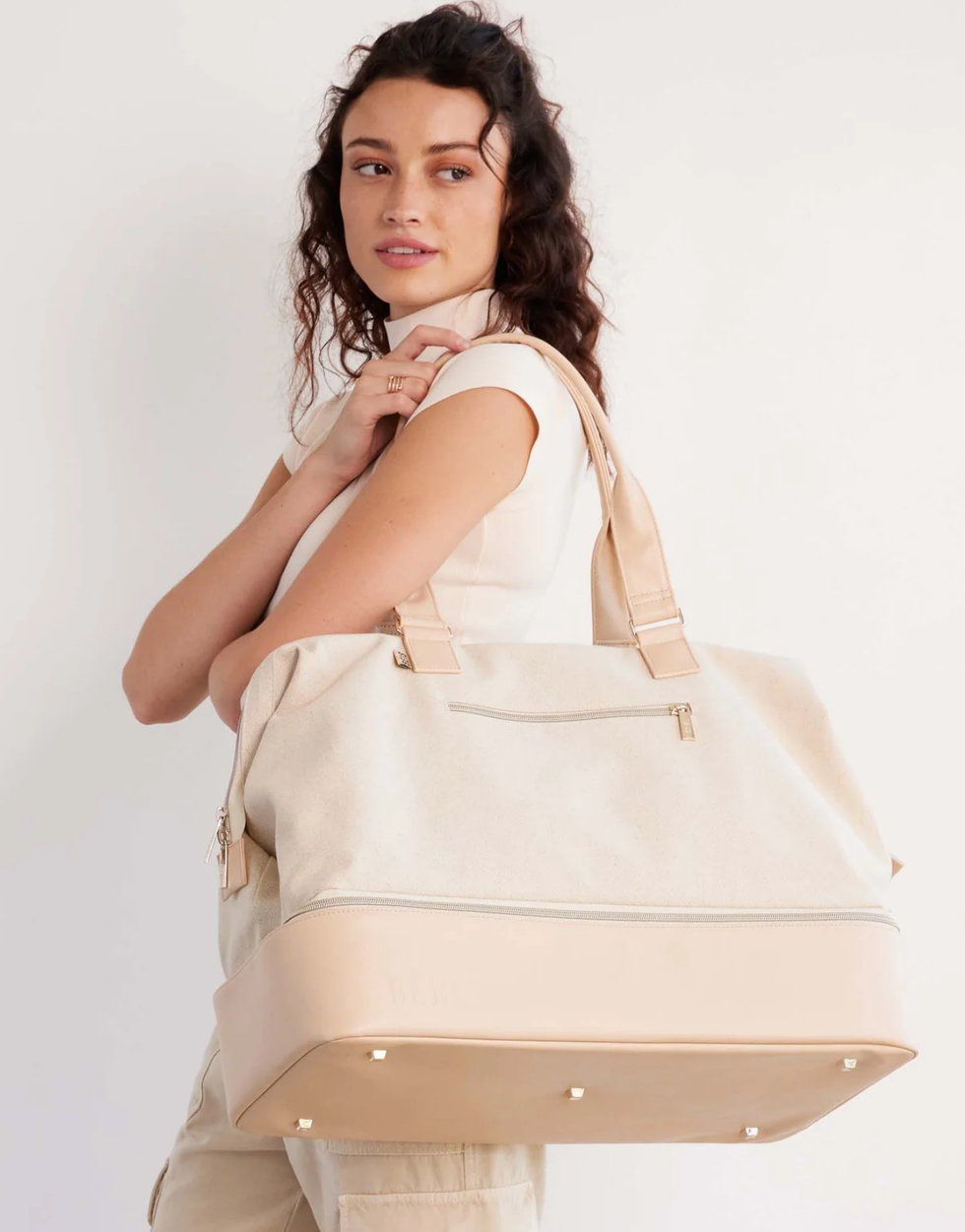 A woman carrying a beige bag.